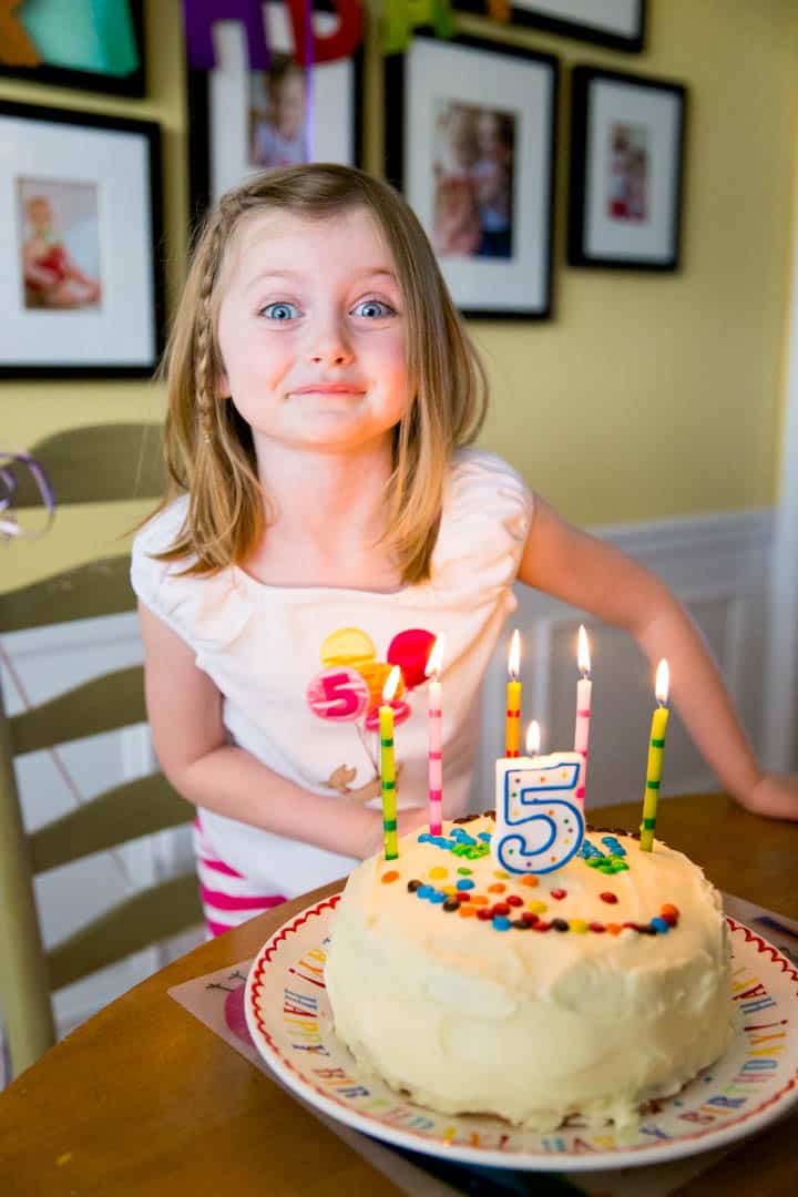 A 5 year old girl is about to blow out the candles on her cake.