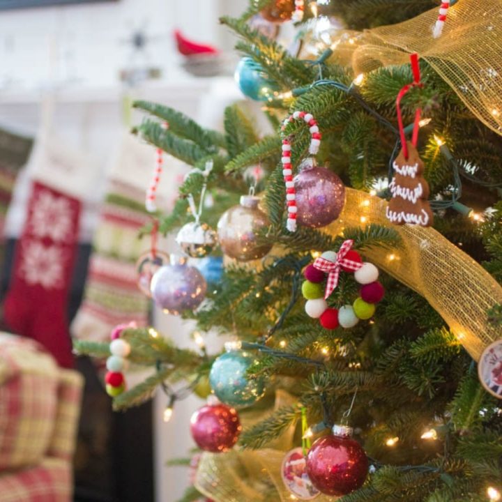 A Christmas tree is decorated with homemade ornaments. You can see stockings in the background.