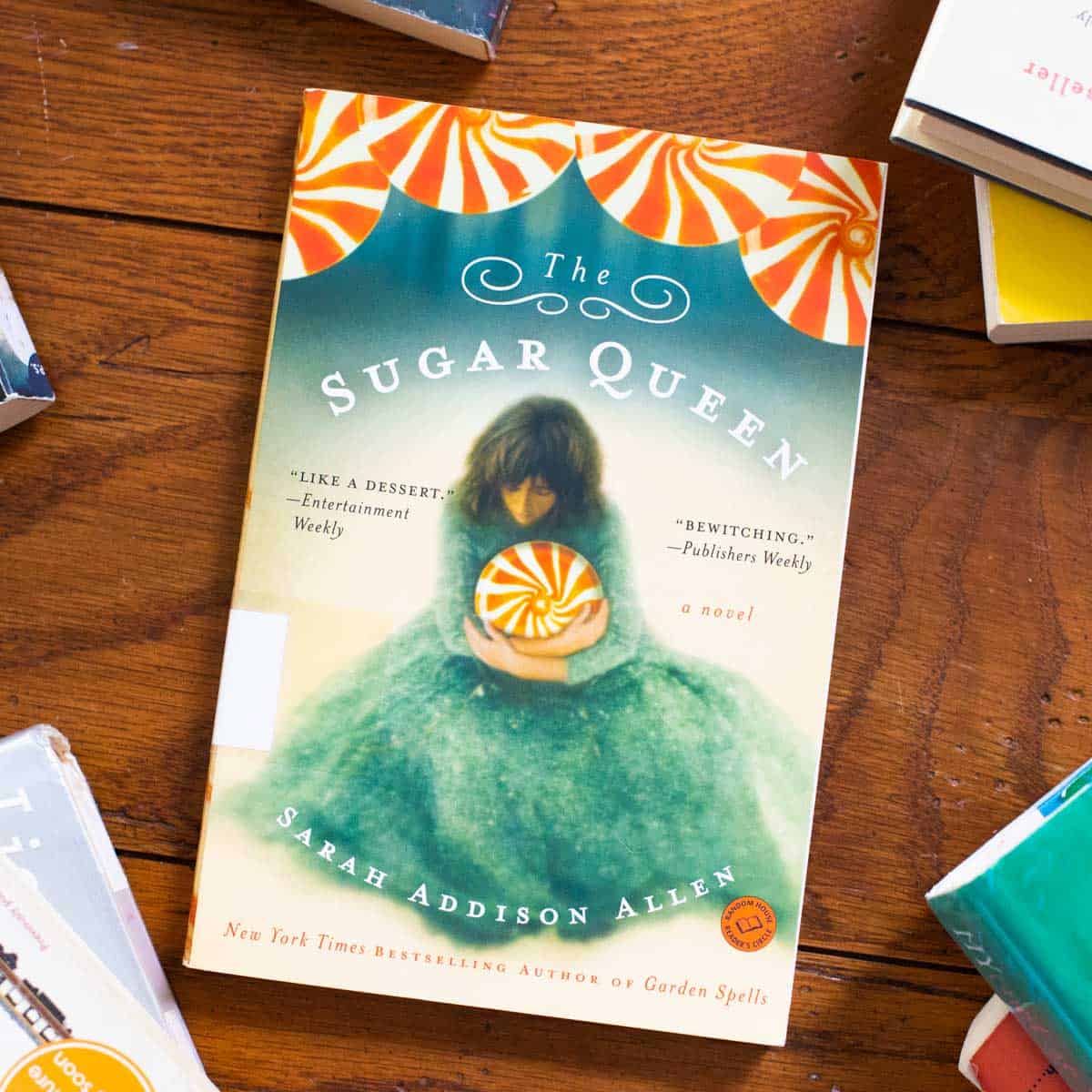 A copy of The Sugar Queen by Sarah Addison Allen sits on a table.