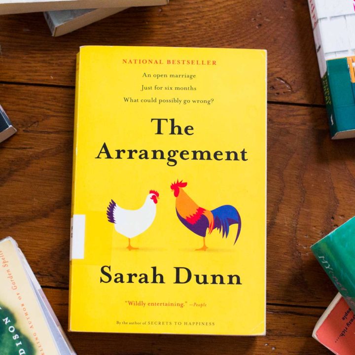 A copy of The Arrangement by Sarah Dunn sits on a table.