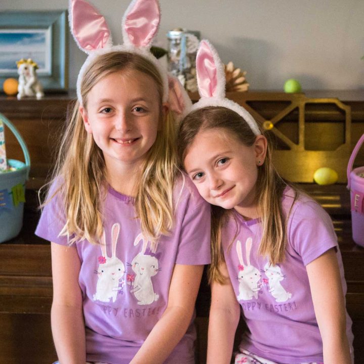 How to take better Easter morning photos of your kids: sisters wearing bunny ears and pastel pajamas sit together on a piano bench.