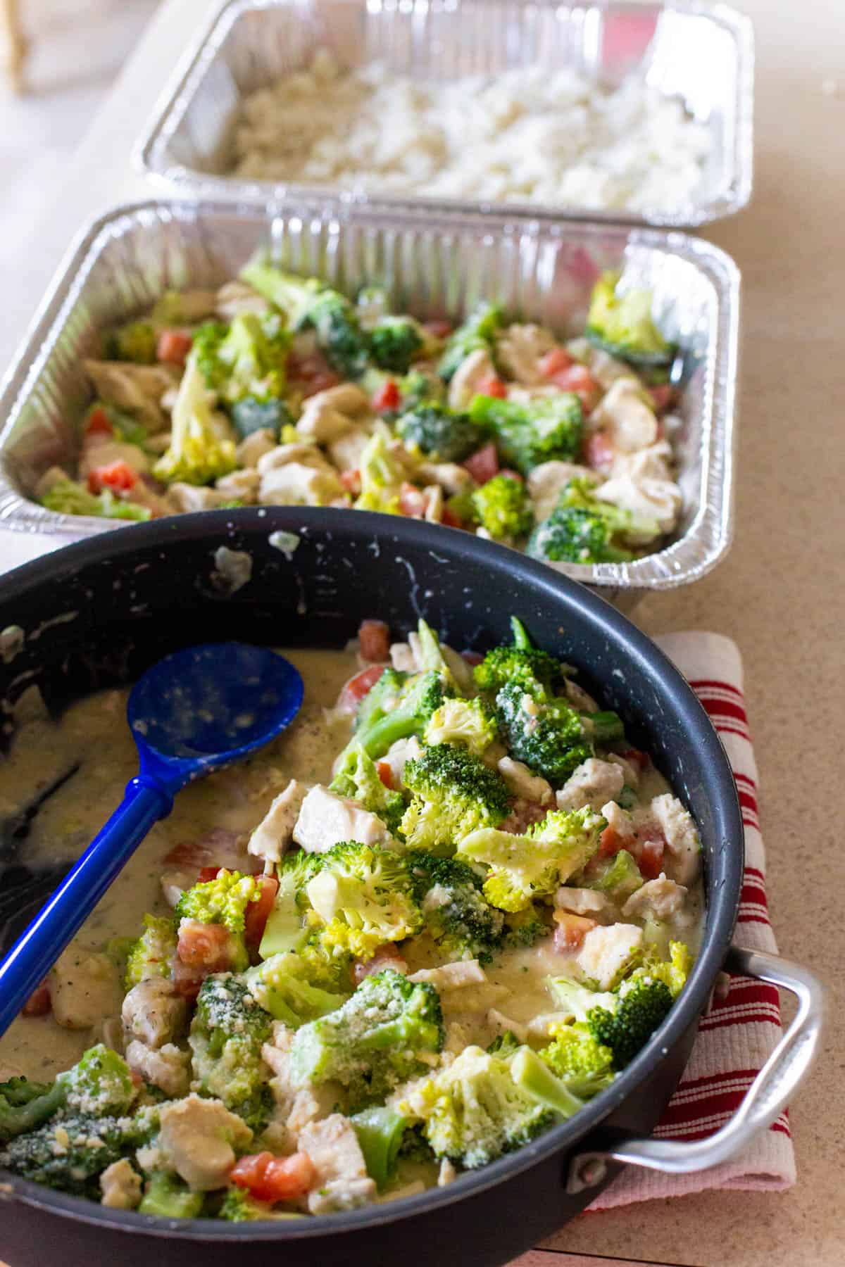 The skillet of casserole filling is sitting next to the freezer pans filled with rice.