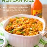 Homemade Mexican Rice in a white baking dish with hot sauce in the background.