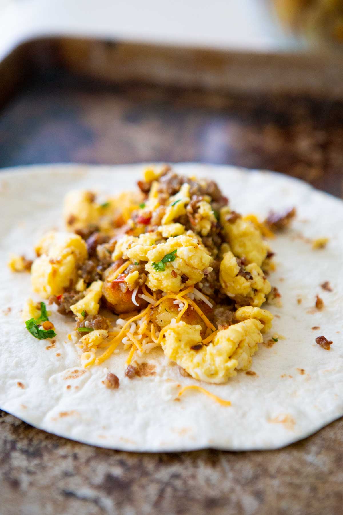 The scrambled egg and sausage filling has been scooped onto a tortilla.