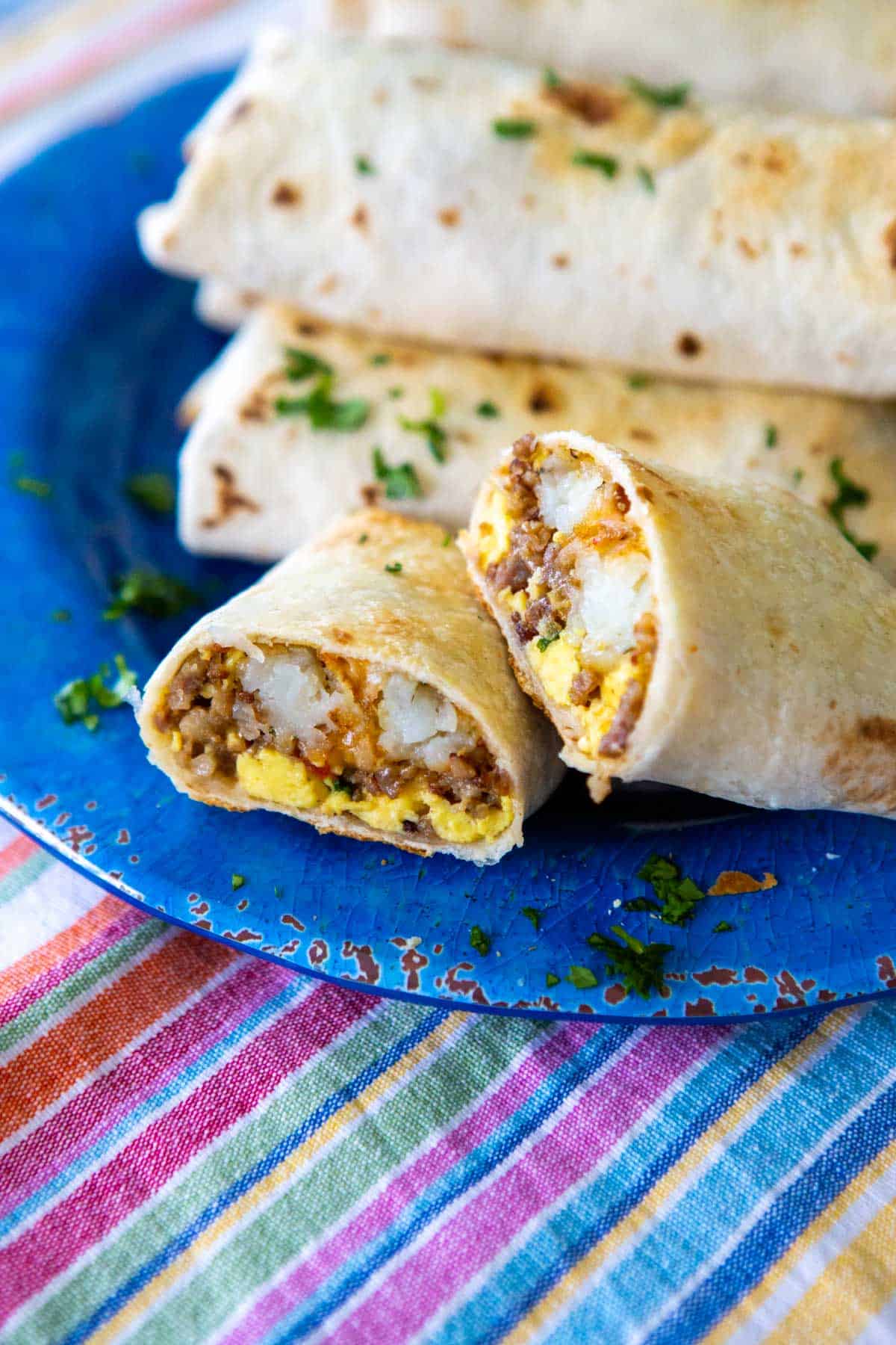 The blue plate has a stack of baked breakfast burritos on it.