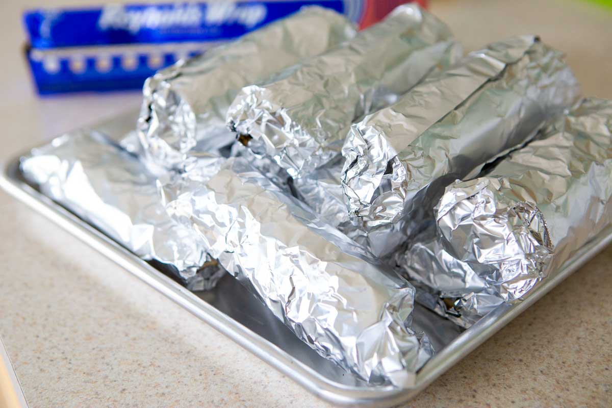 The burritos are wrapped in aluminum foil for the freezer.