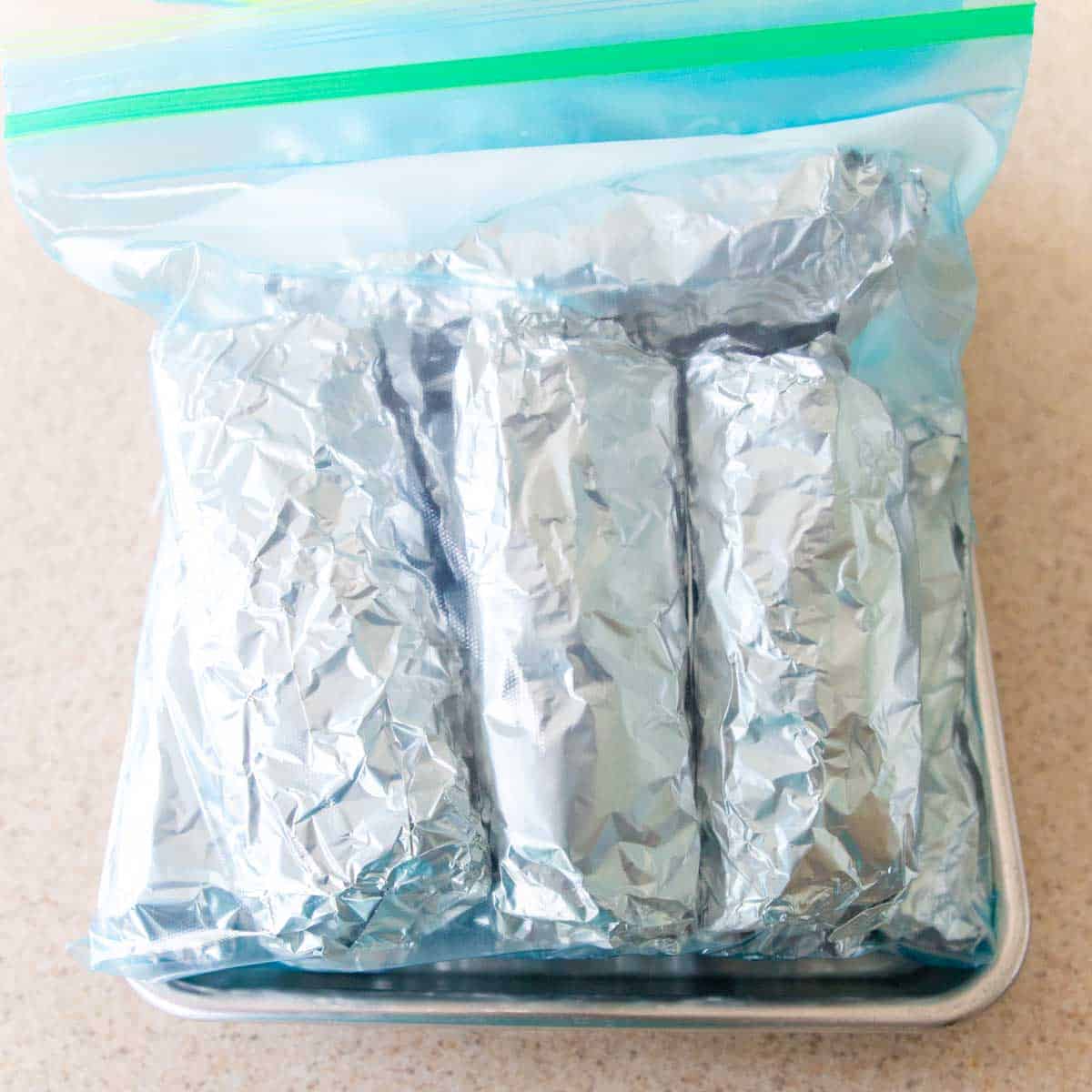 The burritos are wrapped in foil and tucked inside a large plastic bag for the freezer.