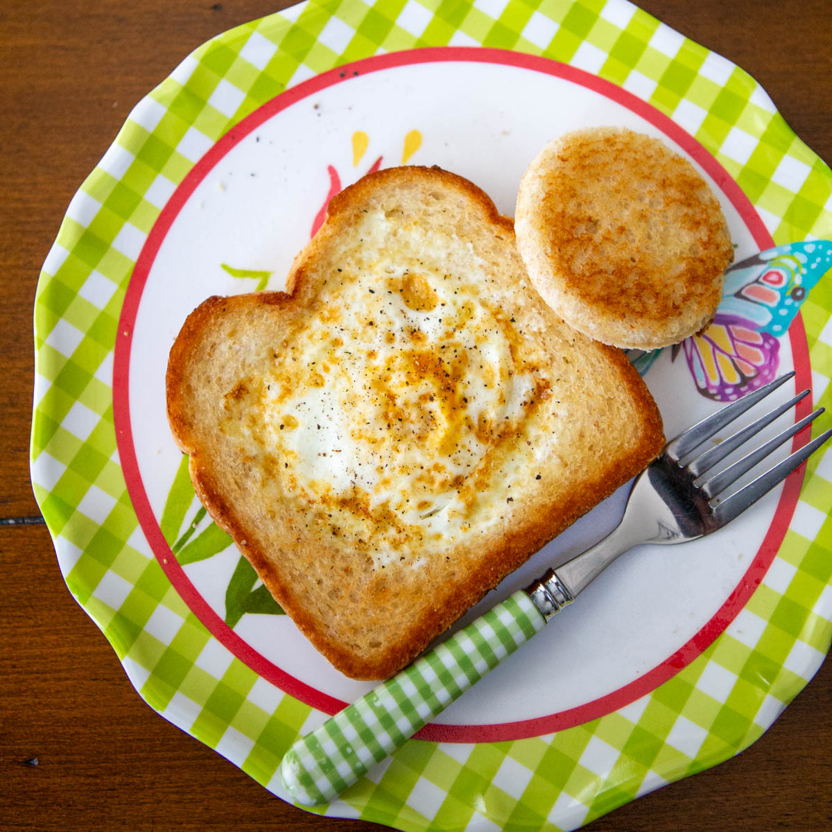 The finished egg in a basket toast is on a plate with a fork.
