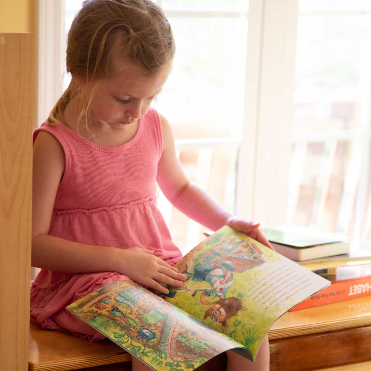 A young girl reads a picture book during summer break.
