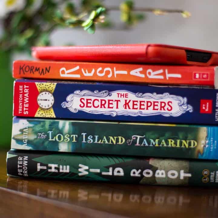 A stack of middle grade fiction books with a Kindle reader on top.