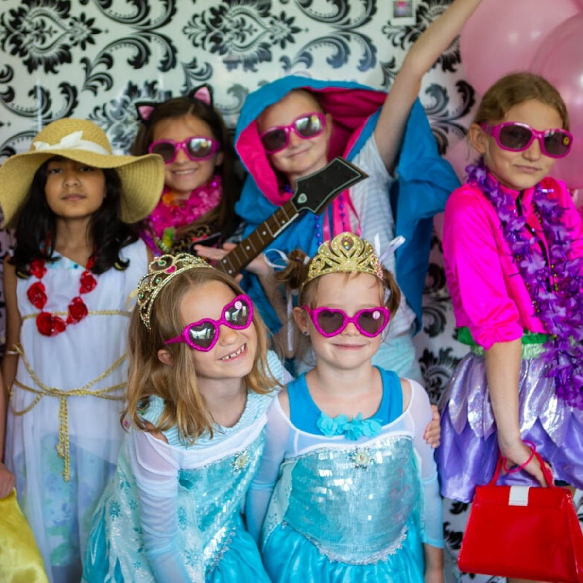 A group of young girls play dress-up at a Barbie birthday party.