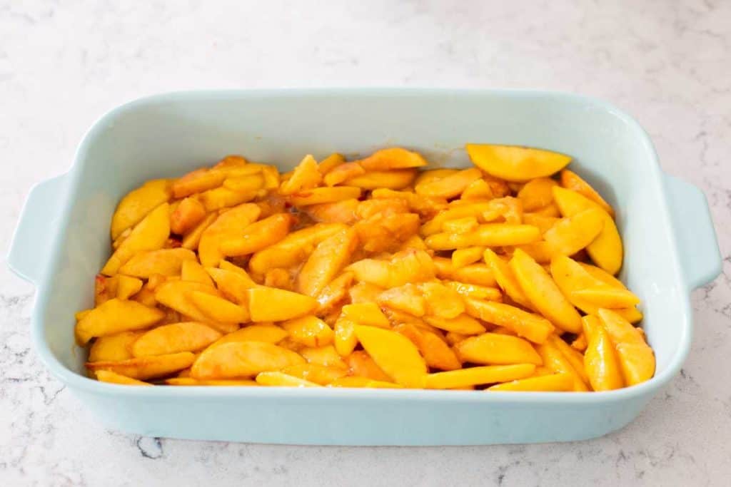 Prepared peaches in the bottom of a 9x13-inch baking dish.