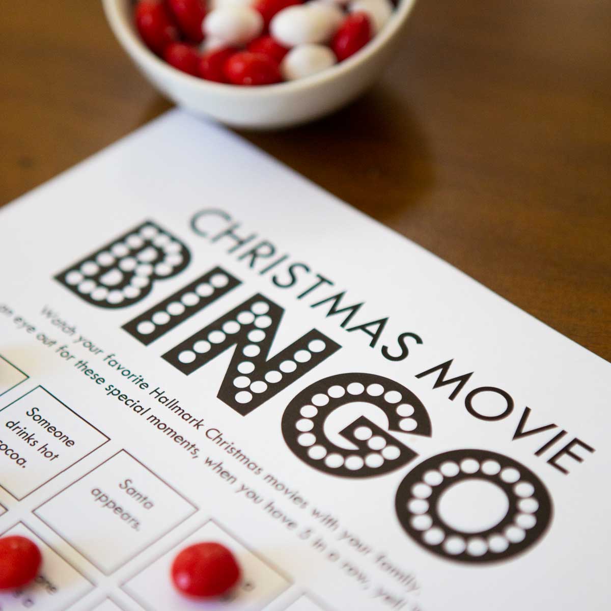 Christmas movie bingo game has red candy markers holding place.