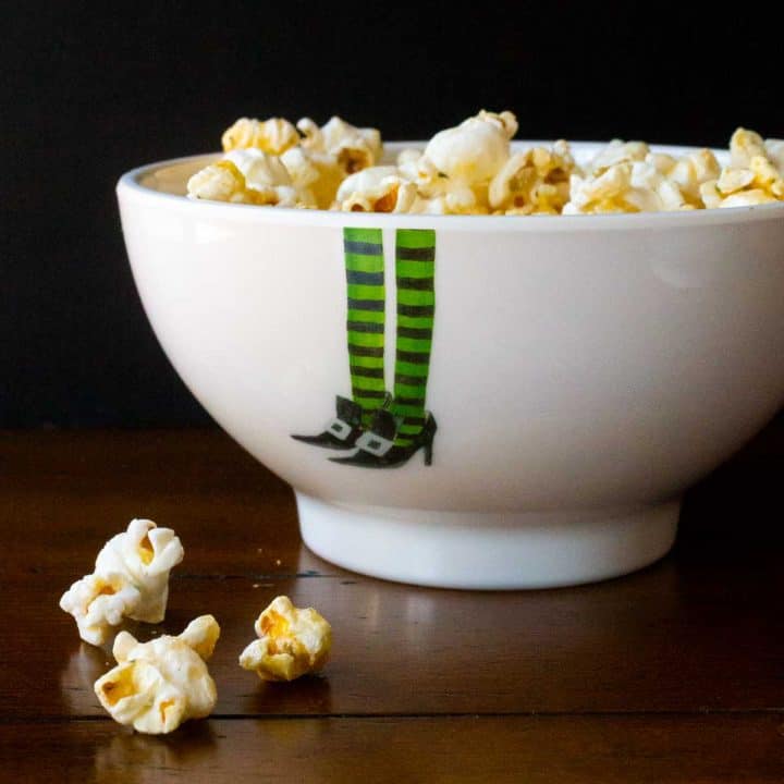 A bowl of popcorn has witch legs on the bowl.