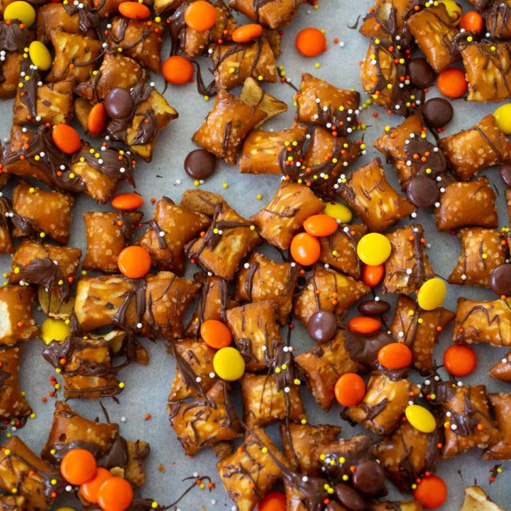 Pretzel nuggets have drizzled chocolate over them and orange and yellow candies.