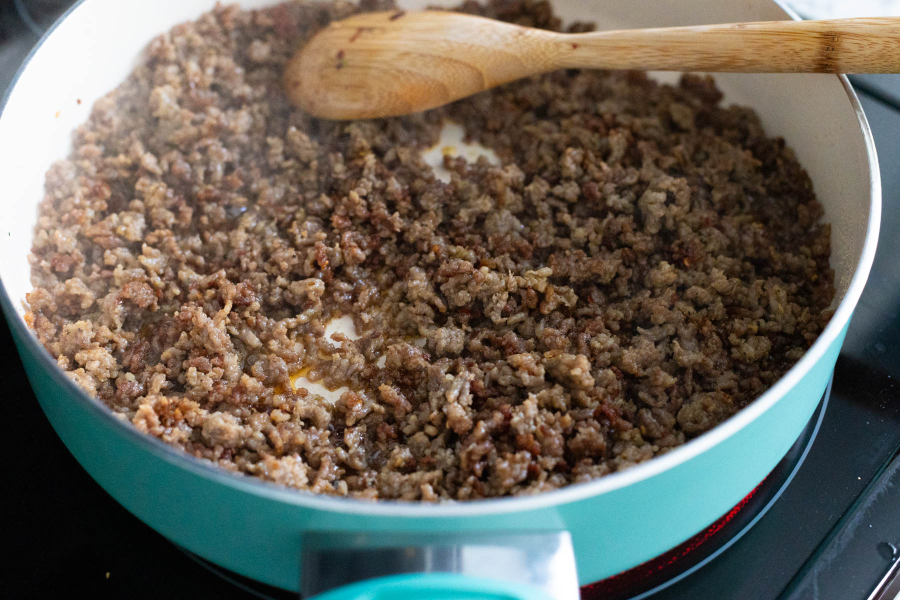 The sausage has been cooked and crumbled in a large skillet.