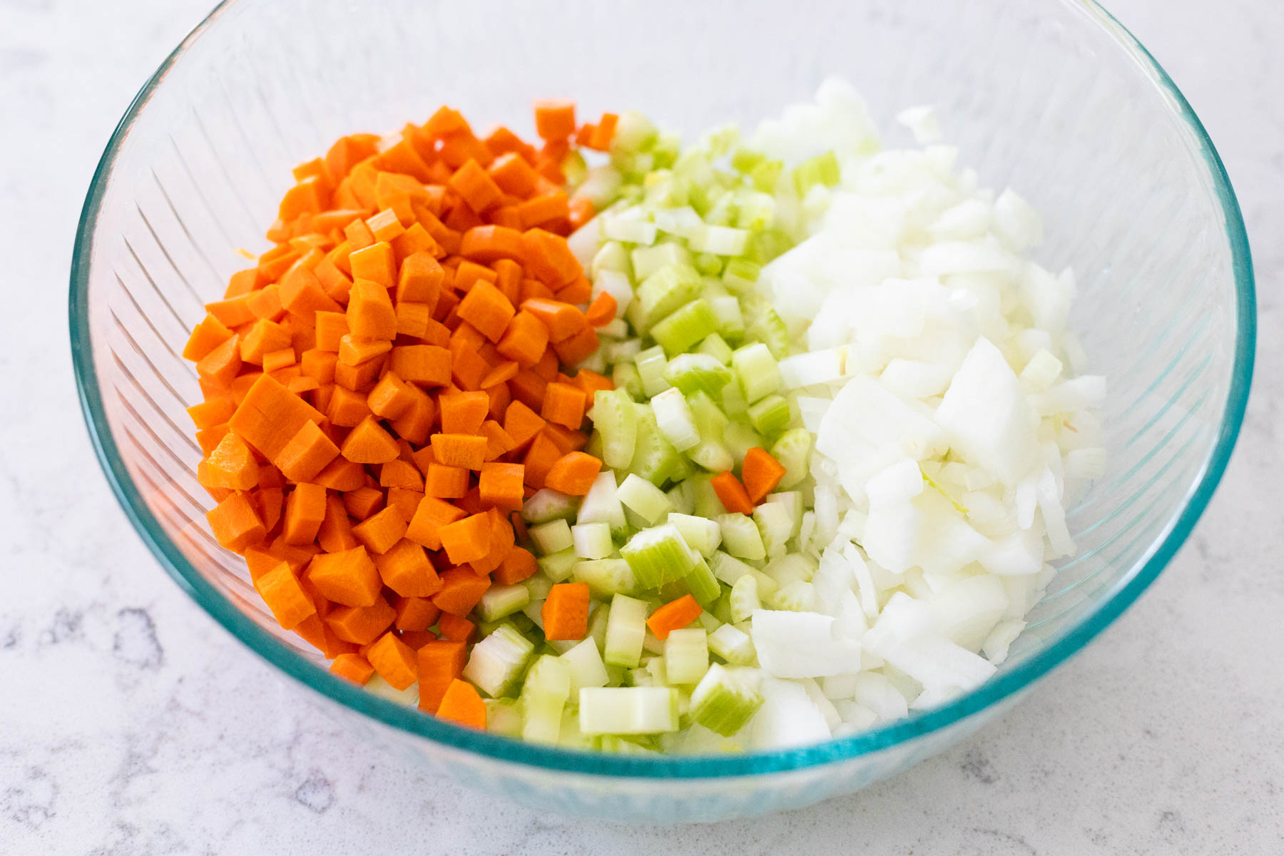 The diced carrots, celery, and onions are in a large mixing bowl.
