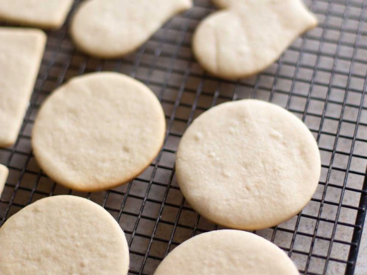 A wire rack has heart-shaped and circle-shaped undecorated sugar cookies cooling.