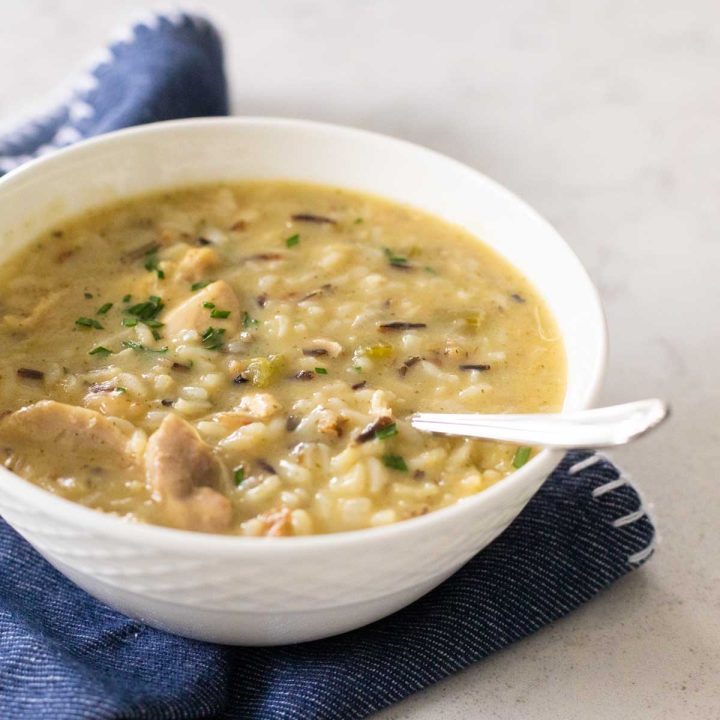 A white bowl is filled with a creamy chicken and wild rice soup.