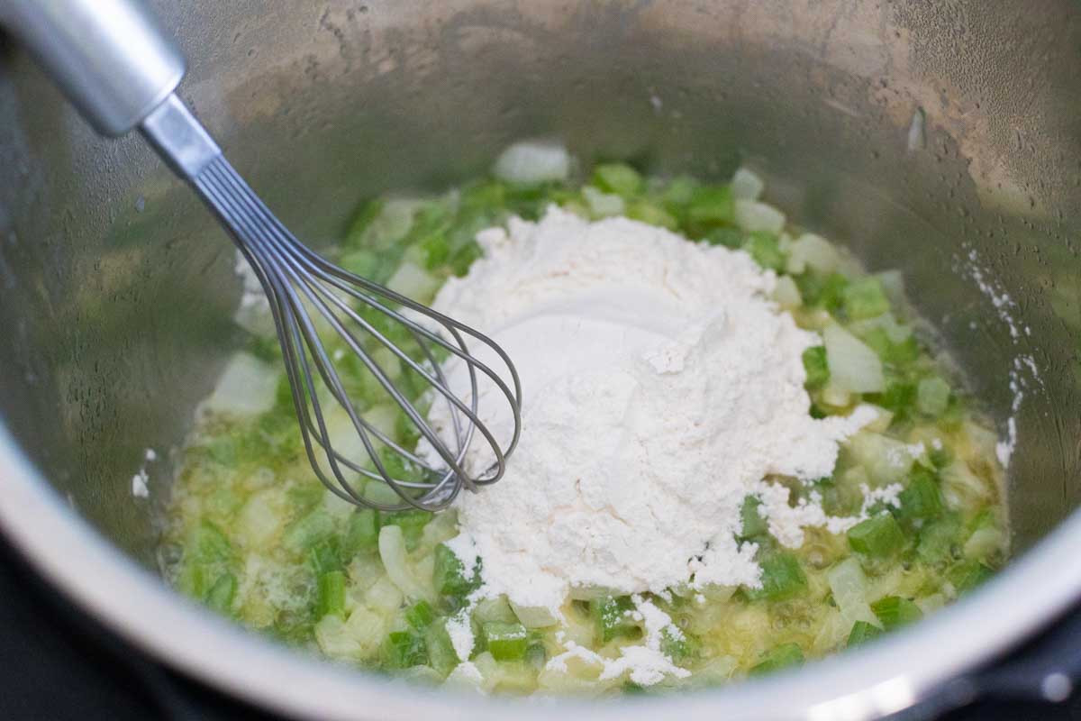 The flour is being whisked into the melted butter with onions and celery.