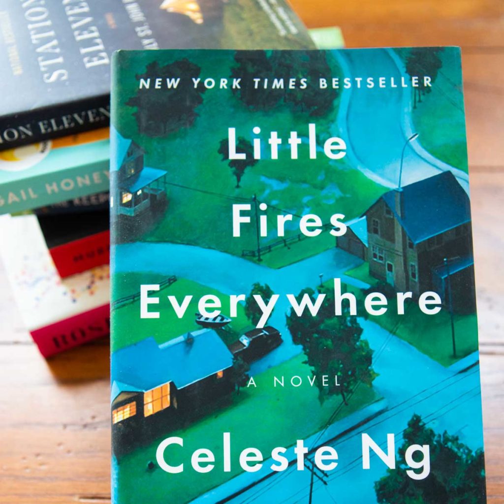 A copy of Little Fires Everywhere rests against a pile of books.