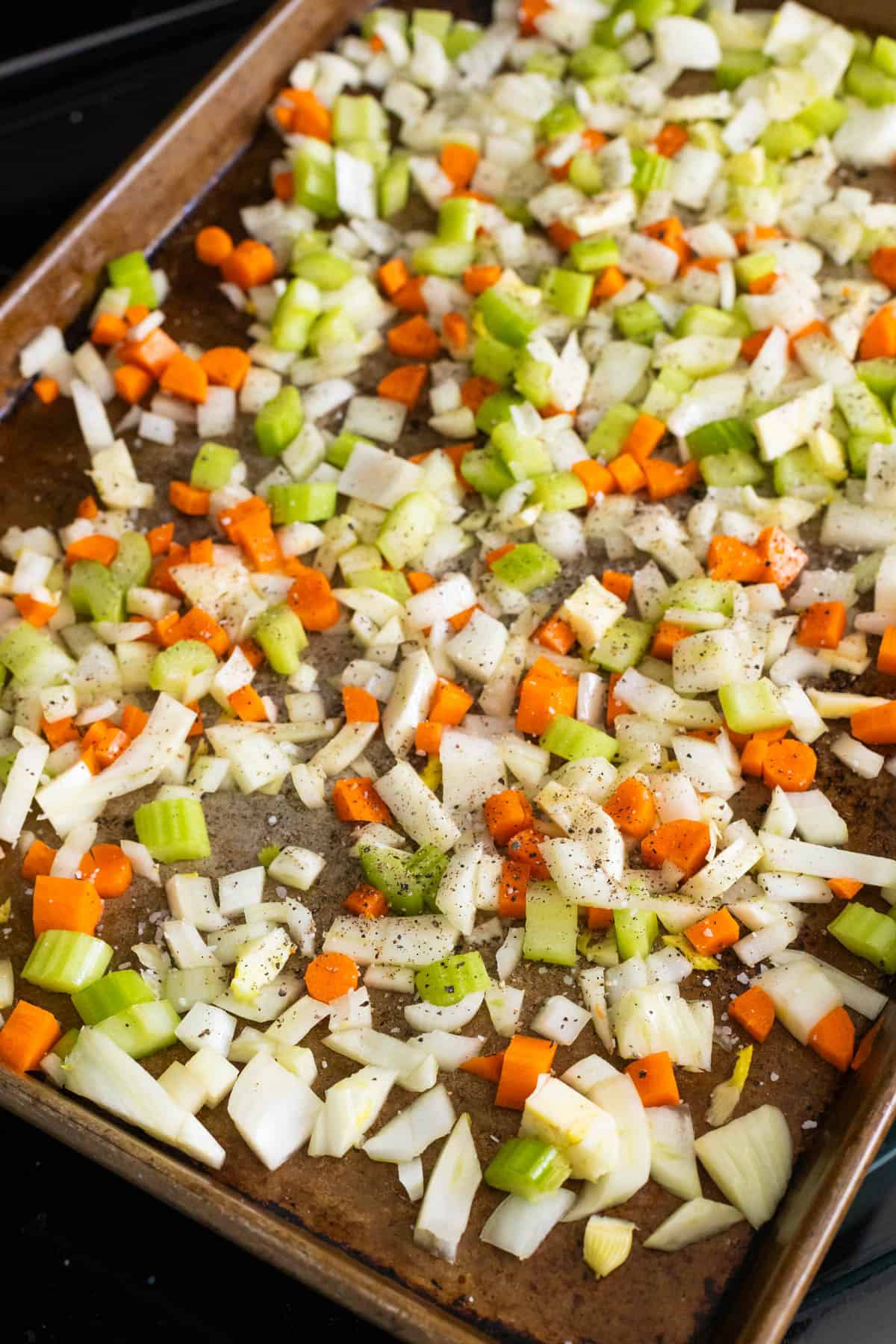 The chopped celery, carrots, onion, and fennel are on a roasting pan.