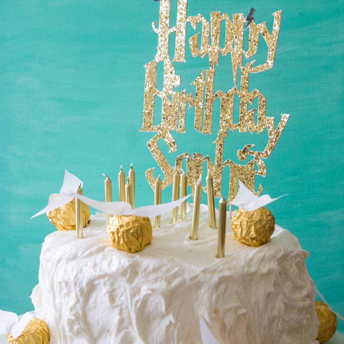 White Harry Potter cake covered in golden foil golden snitches.