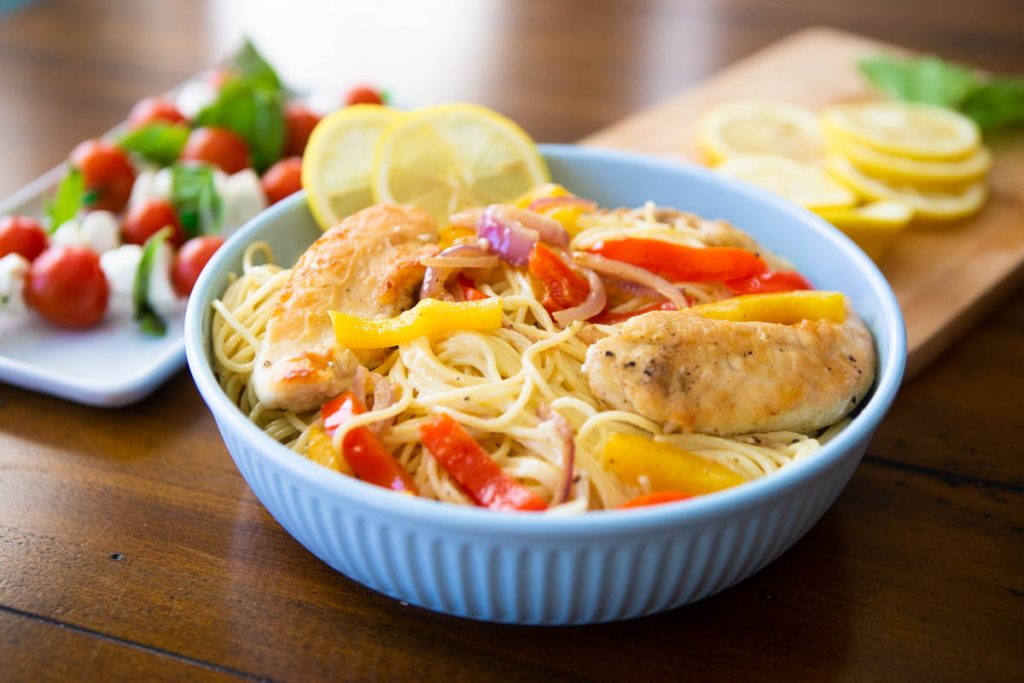 A bowl of chicken scampi sits on a dinner table.