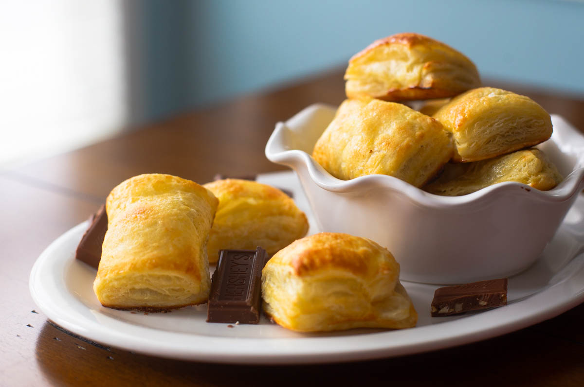 A white platter of chocolate croissants has chocolate squares scattered throughout.