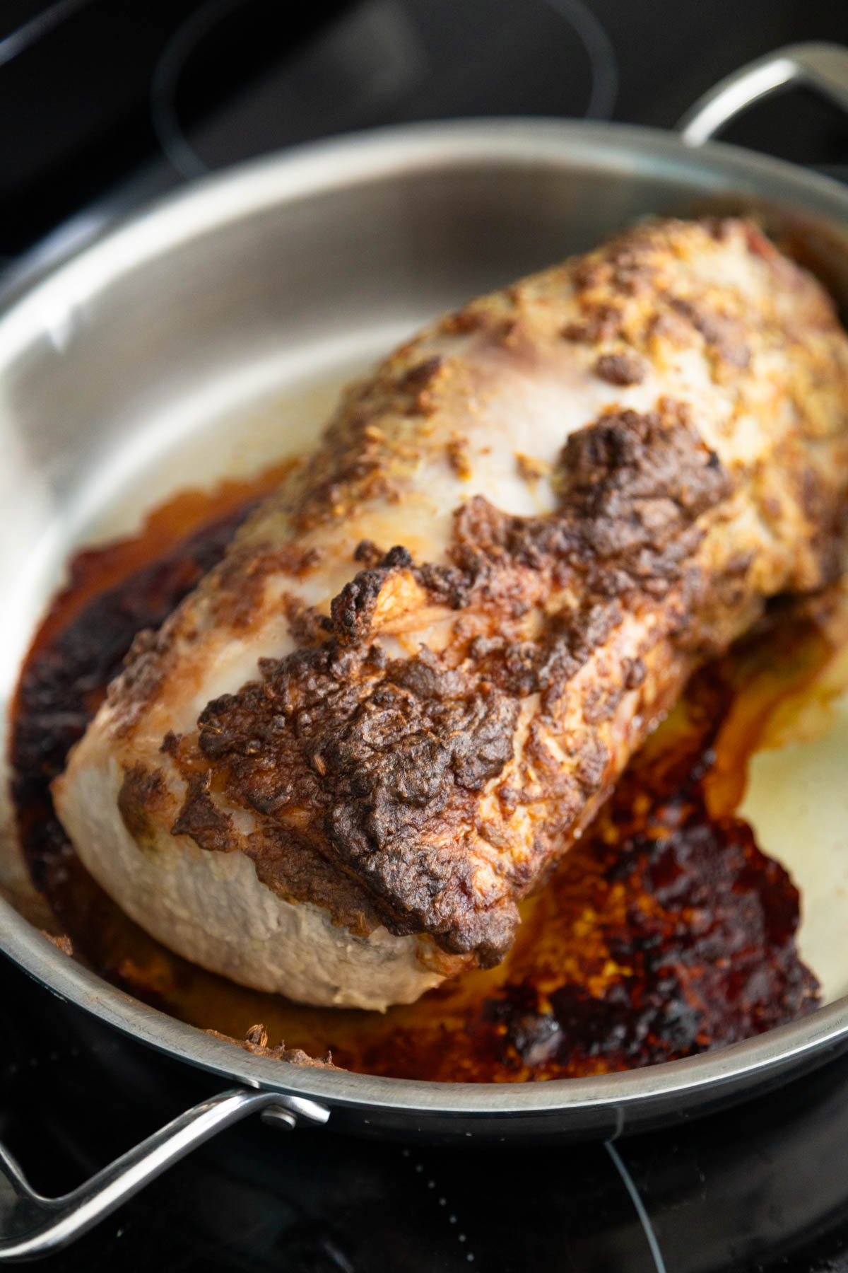 The pork loin has finished roasting and has deep brown crispy edges.