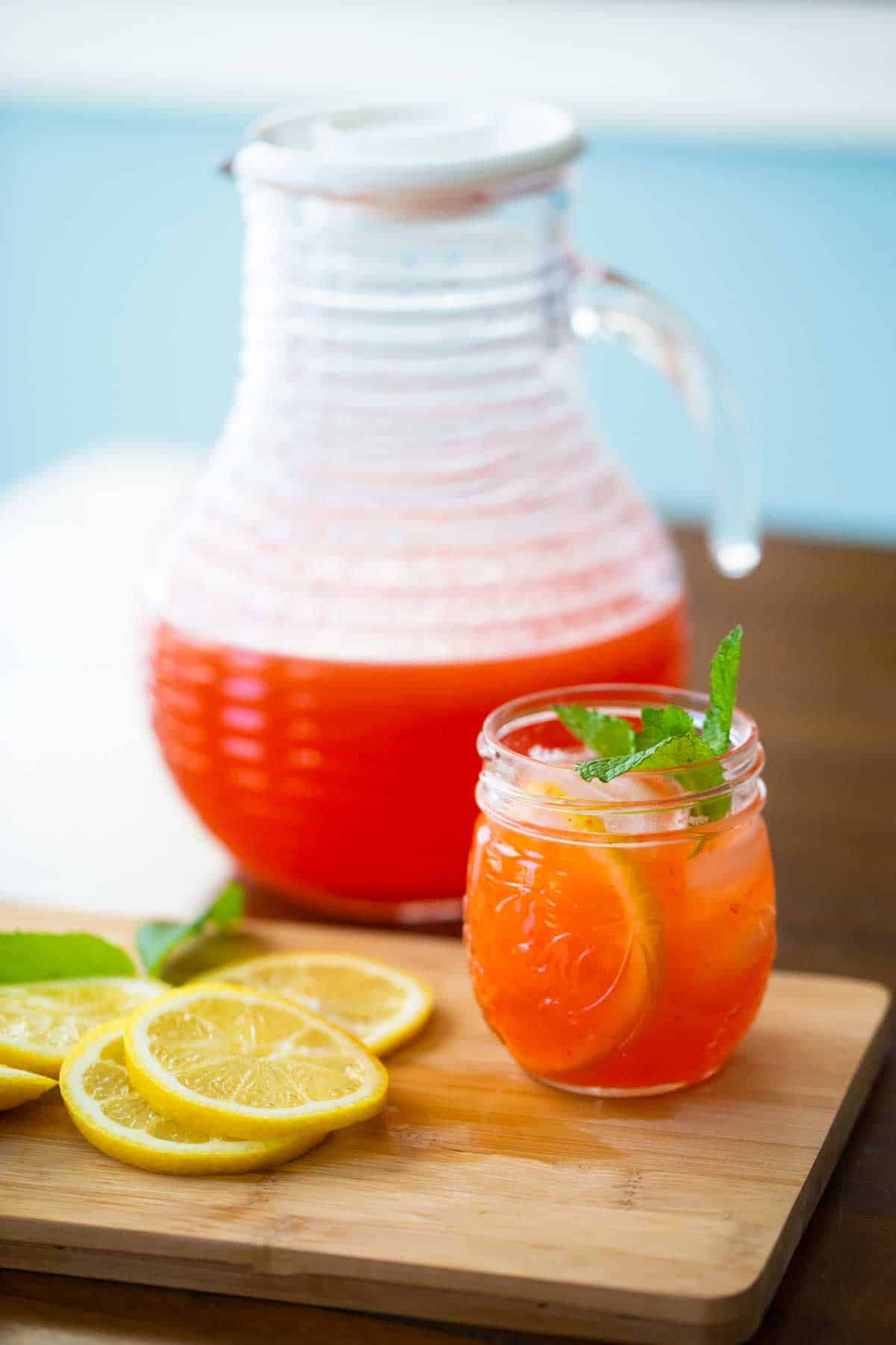 The lemonade is in a pitcher. A glass of lemonade with fresh mint sits in front.