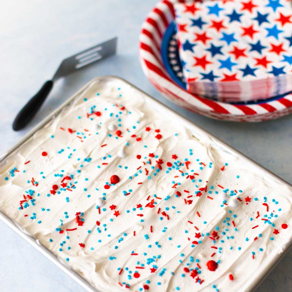 The finished ice cream sandwich cake sits next to red, white, and blue starred party supplies.