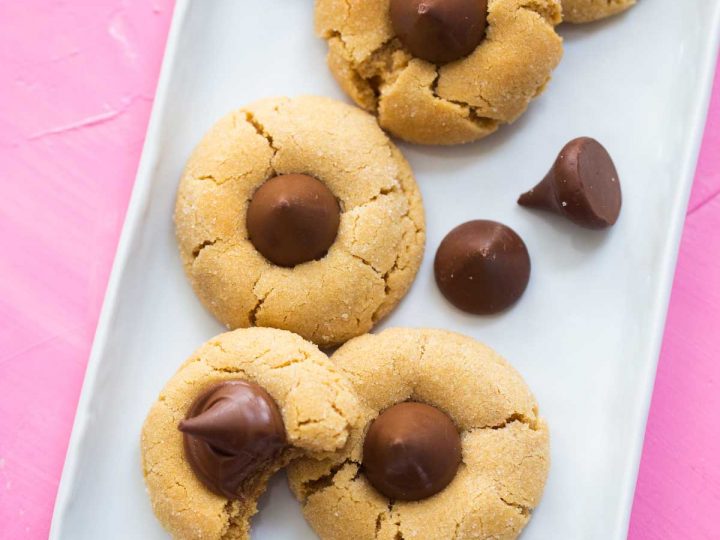 A tray of peanut butter blossom cookies with hershey kisses on top.