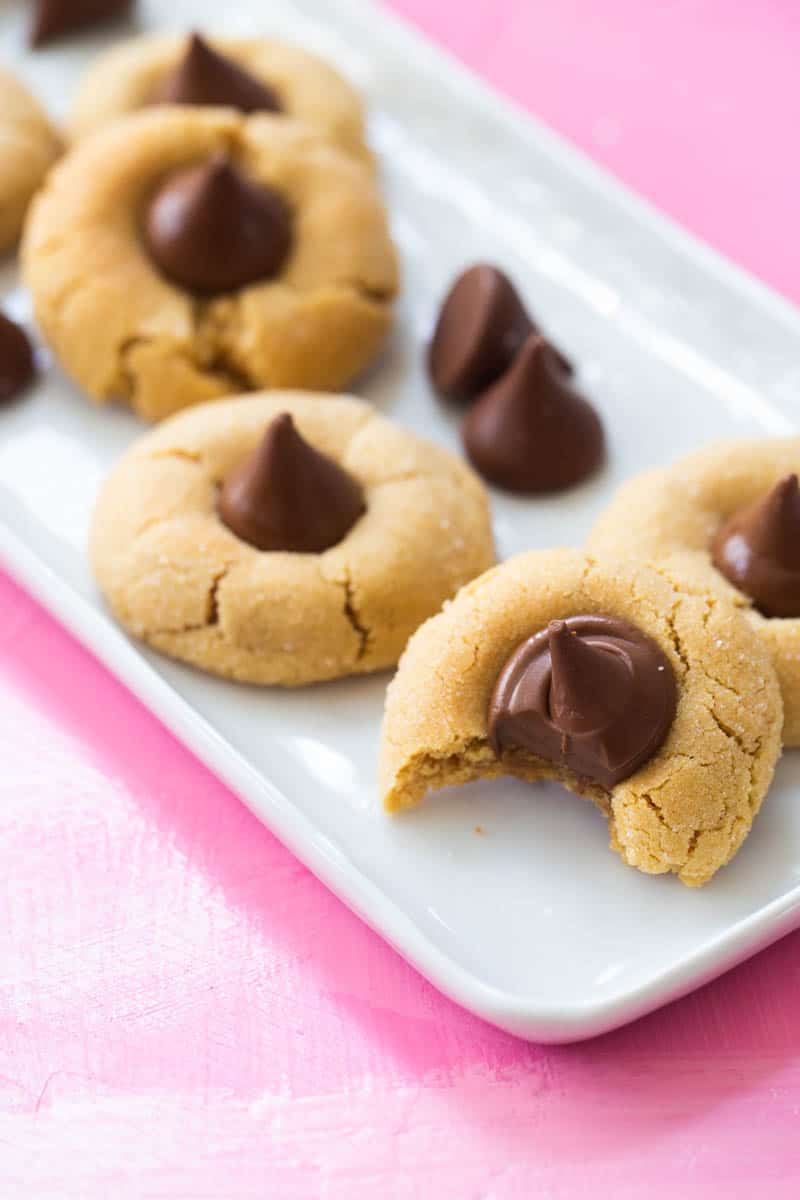 A white platter has several peanut butter blossom cookies on it.