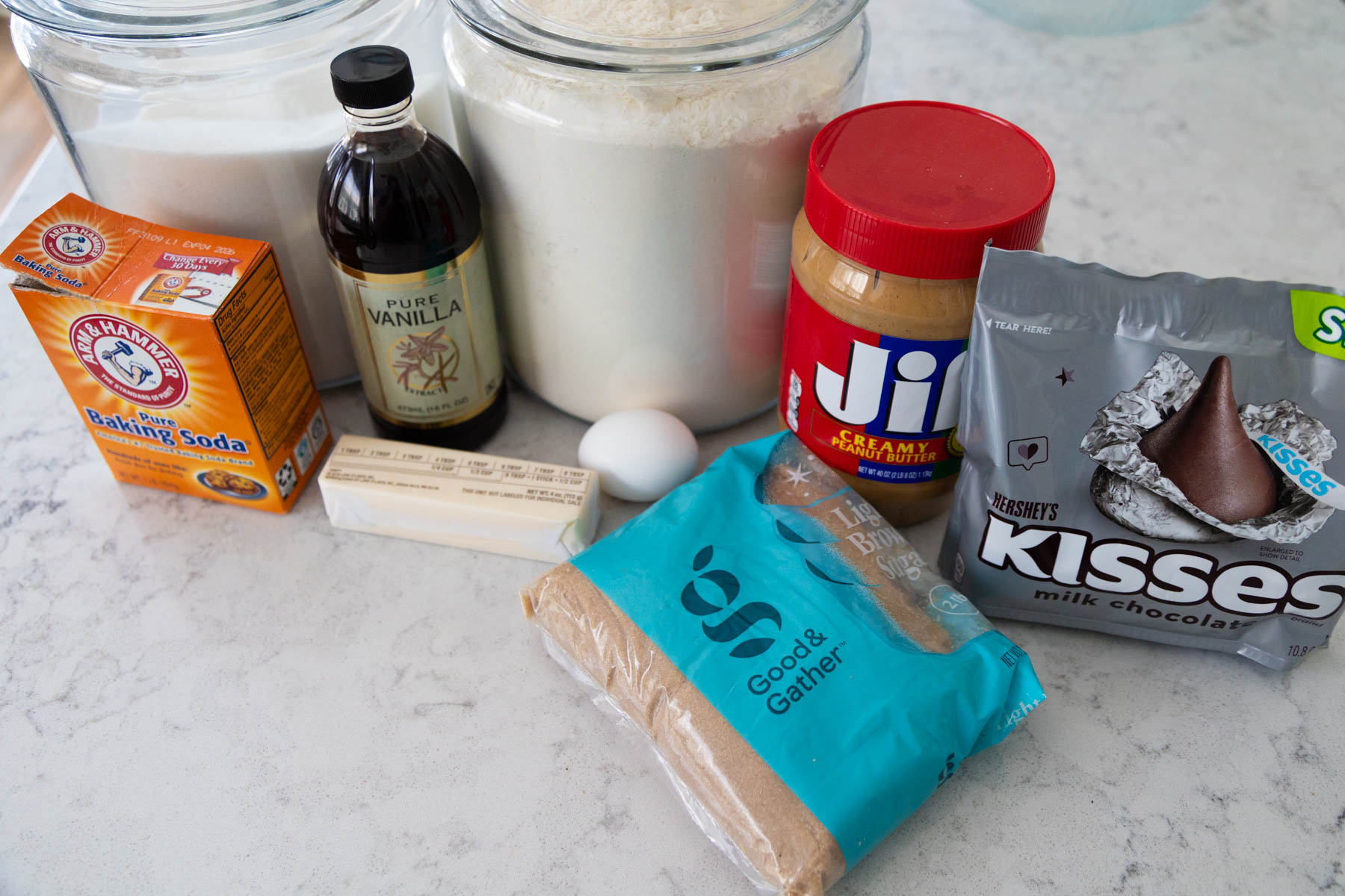 The ingredients to make peanut butter blossom cookies are on the counter.