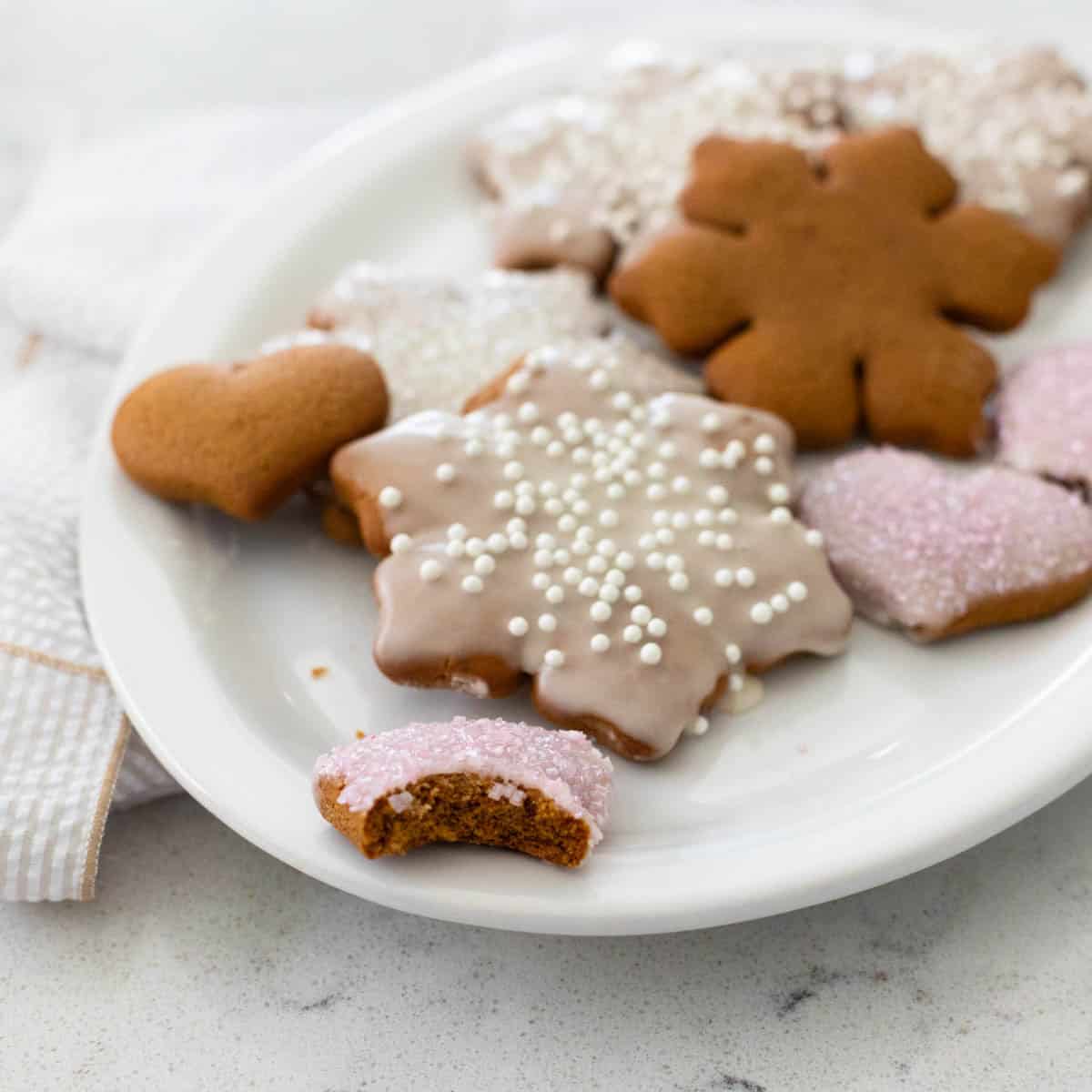 Un plat blanc rempli de biscuits en pain d'épices glacés en forme de flocons de neige et de cœurs.