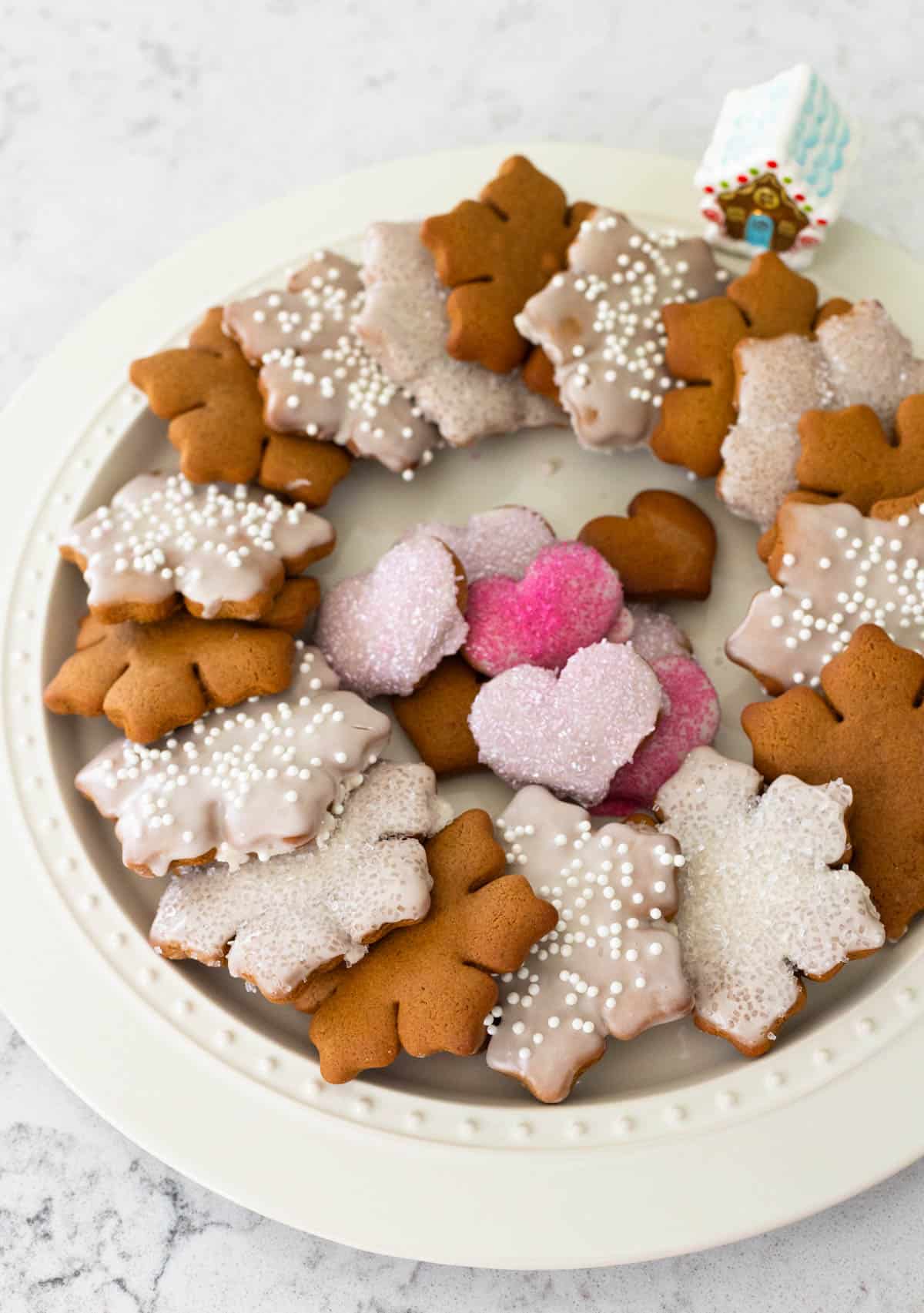 The large white cookie platter is filled with iced gingerbread cookies.