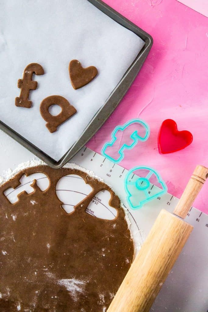 The dough has been rolled out and letter-shaped cookies have cut out the letters "F" and "A".