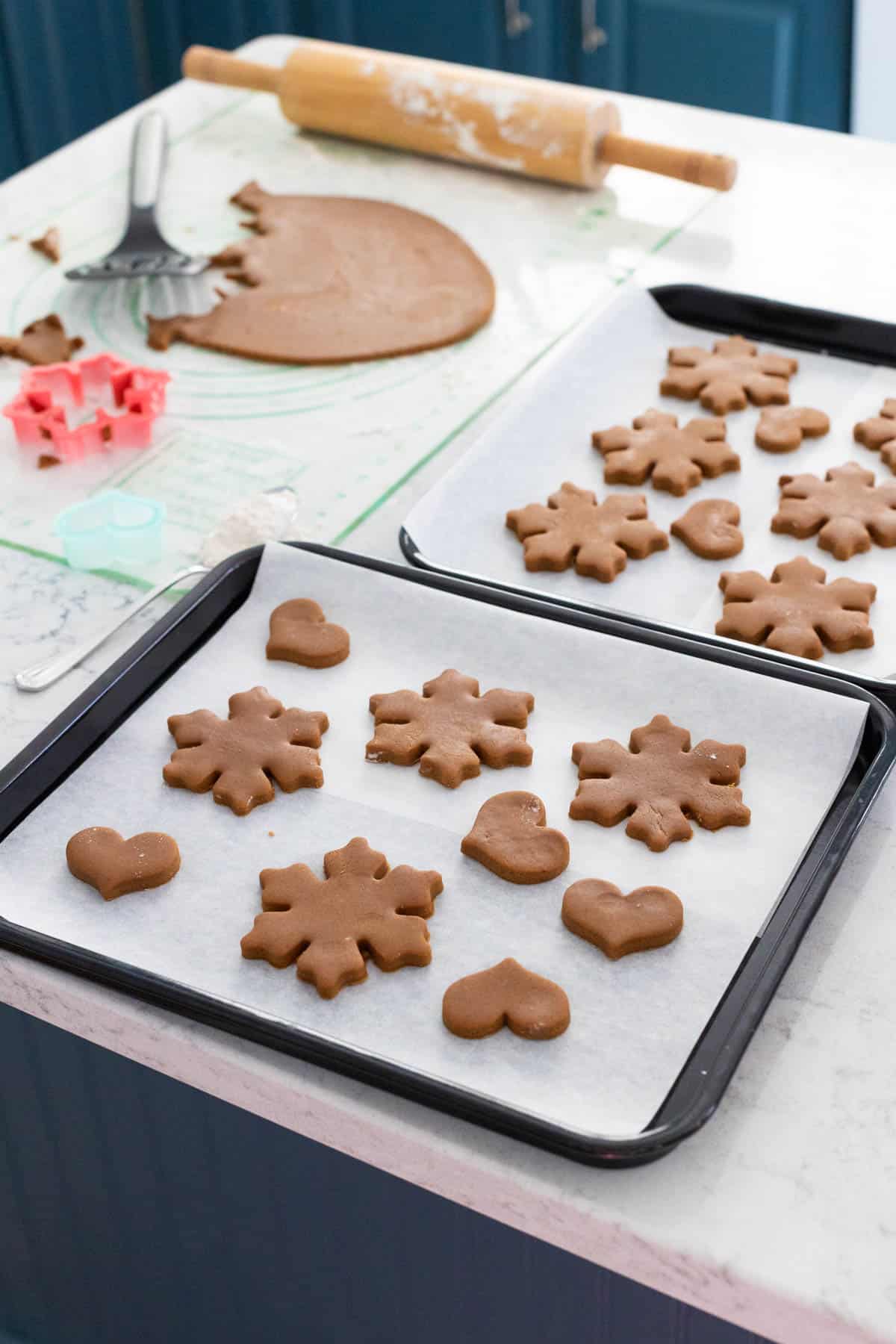 The baking pans are filled with cut out cookies and are ready for the oven.