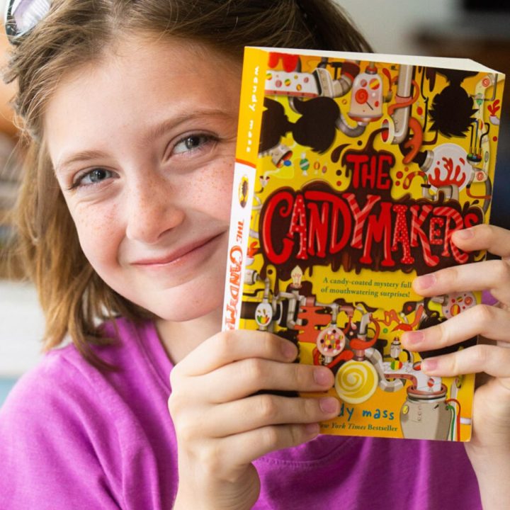 A young girl holds a copy of a book club book.