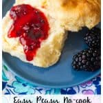 The blackberry jam has been spread on a biscuit sitting on a blue plate.