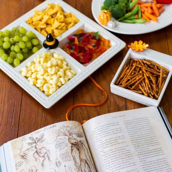 Harry Potter themed snacks are in a platter with a witch hat sitting next to an open copy of a Harry Potter book.