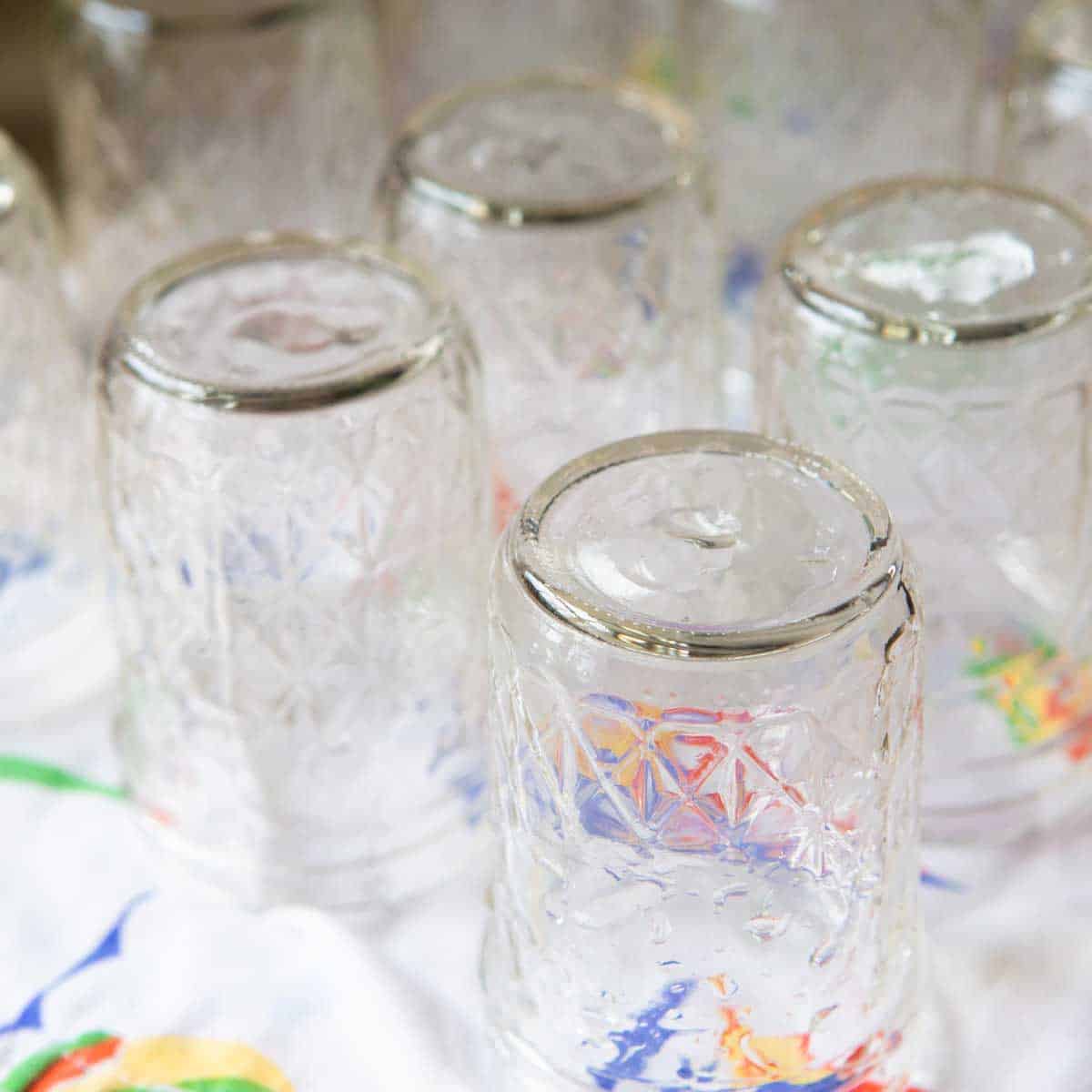 Jelly jam jars are drying upside down on a tea towel.