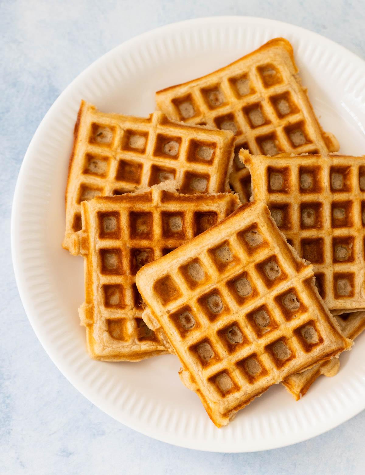 A white plate is filled with 5 golden brown buttermilk waffles.