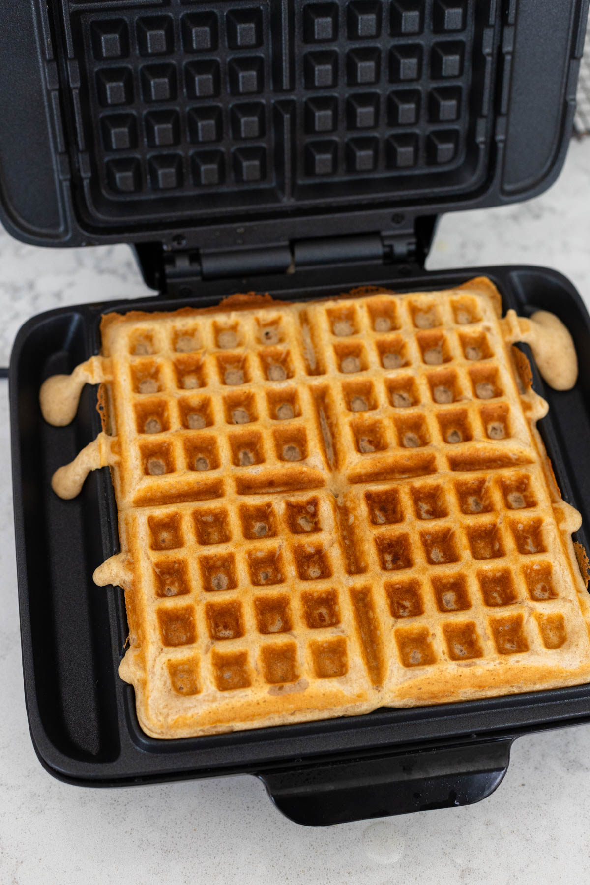 4 buttermilk waffles are now golden brown in the waffle maker.