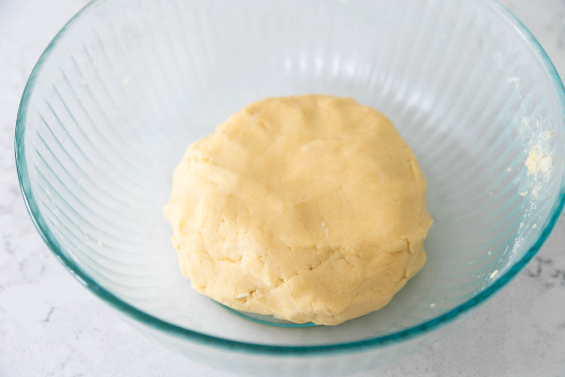 The finished ball of sugar cookie dough rests in a mixing bowl.