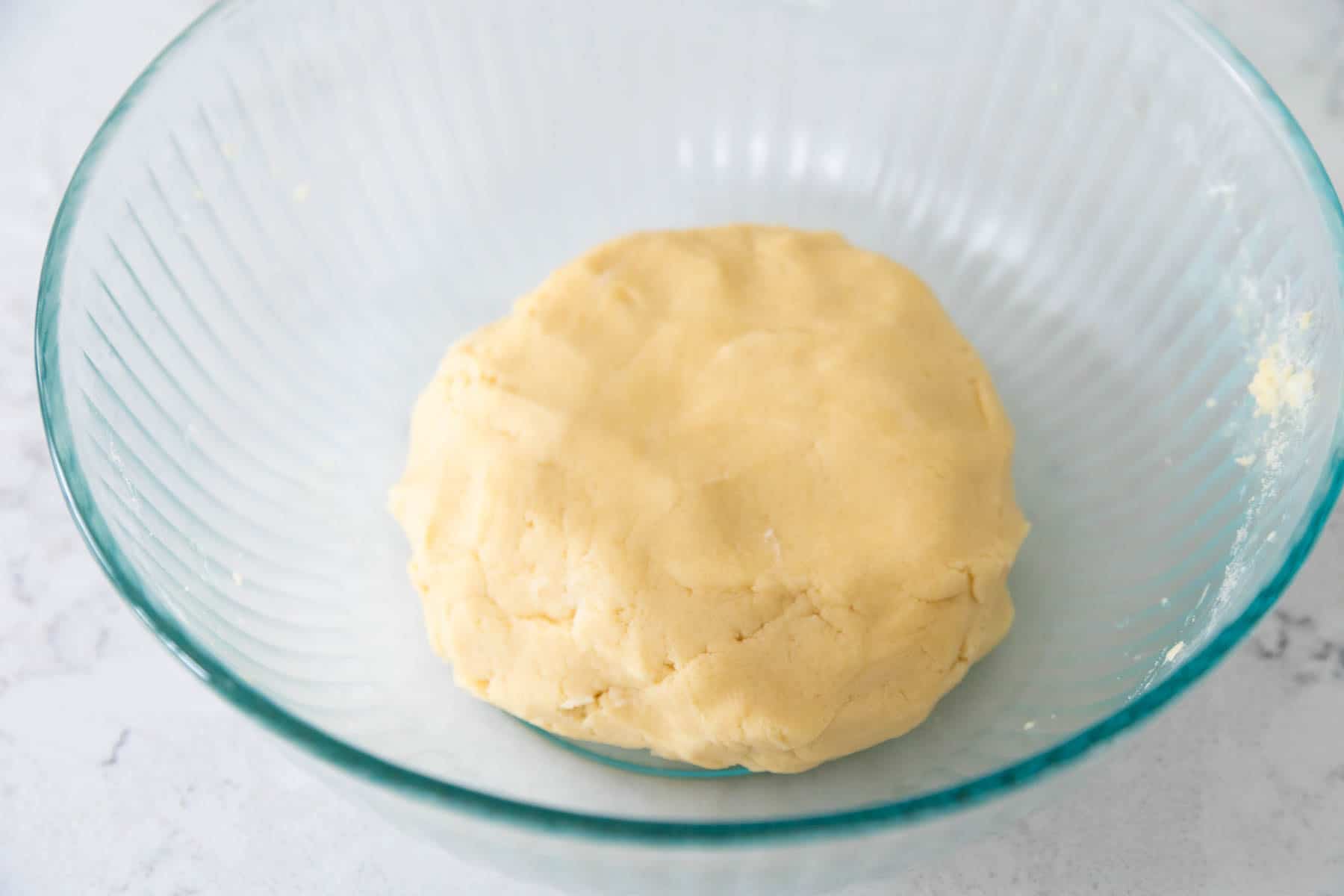 The finished ball of sugar cookie dough rests in a mixing bowl.