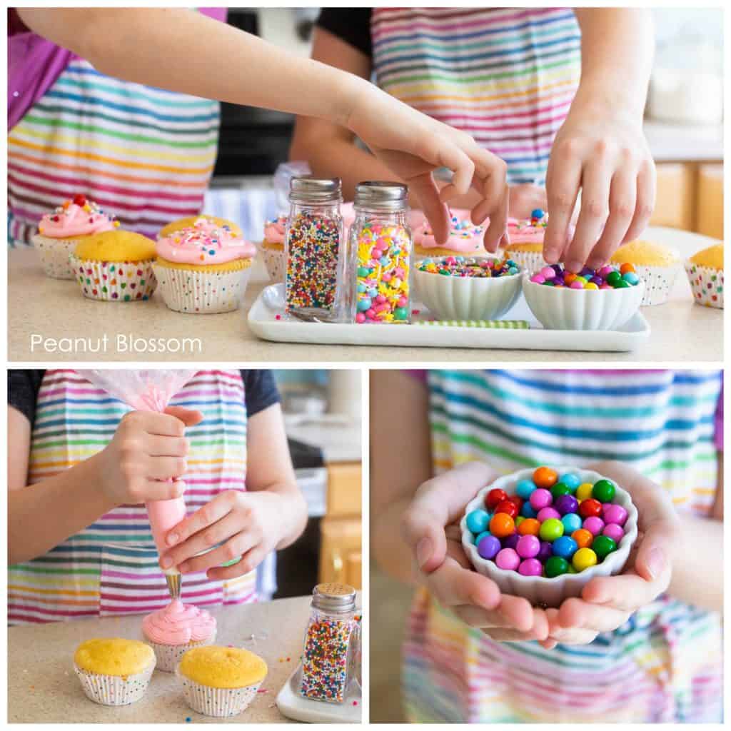 Young kids' hands are pinching sprinkles over cupcakes.