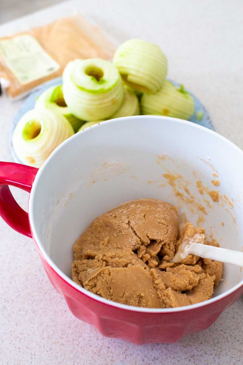 The mixing bowls shows the thick texture of the fresh apple cake dough.