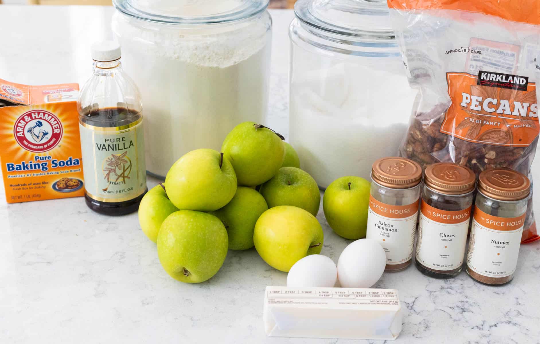 The fresh apples and pantry ingredients are lined up on the kitchen counter.